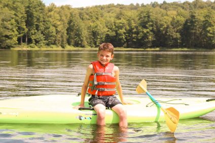 A boy in a green kayak on the lake